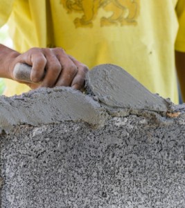 Concrete worker spreading cement and smoothing a concrete surface